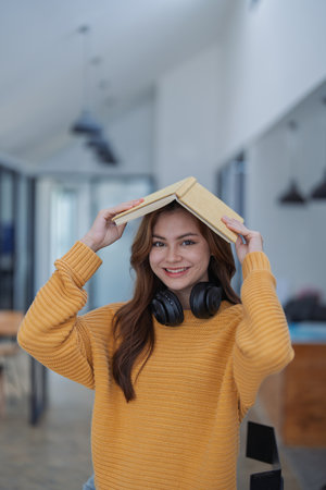 happy young woman with headphones is immersed in a book, happily learning.の写真素材
