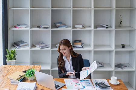 Young businesswoman analyzes financial reports at her office workstation..の写真素材