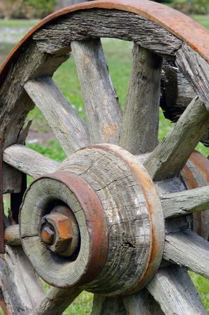 Old, wooden, rustic wagon wheel in a grassy field.の写真素材