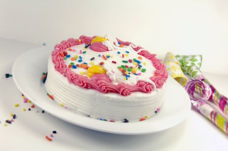 Birthday cake and party blowers on a white background.の写真素材