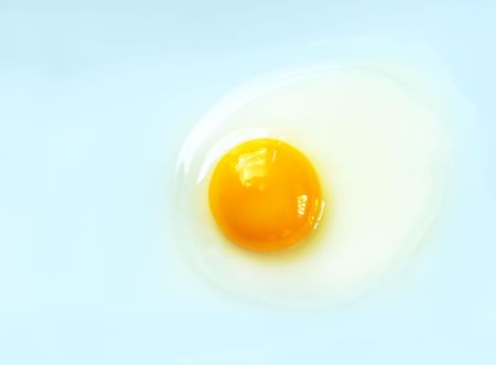 Raw egg on a light blue background with copy-space for your text.の写真素材