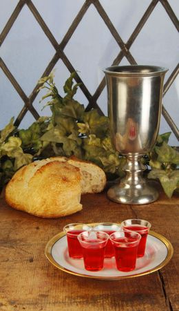 Communion bread and wine on a rustic surface in front of a leaded glass window.の写真素材