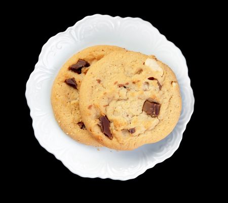 Chocolate chip cookies on a white plate on a black background.