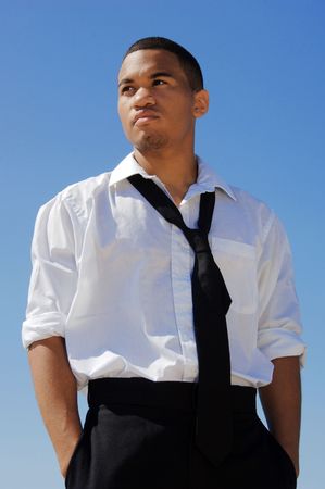Young man in a white shirt and black tie against the blue sky.の写真素材