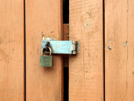 Rusty padlock and hasp on weathered painted wooden doorの写真素材