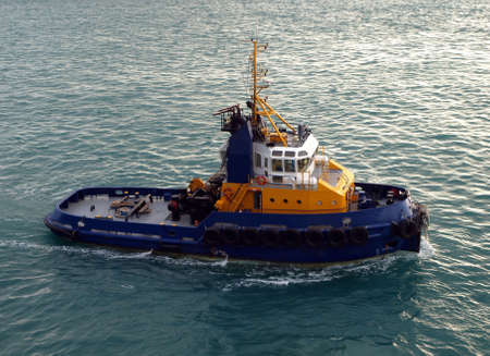 A blue and yellow pilot boat stands ready to lead and assistの写真素材