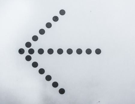 old arrow left black dot on white wall backgroundsの写真素材