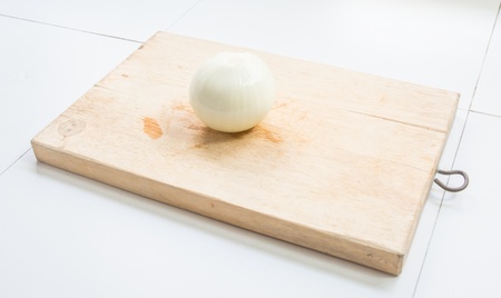 one onion on wood butcher at white tableの写真素材