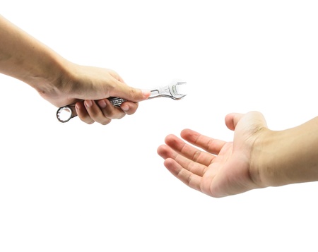 girl hand send wrench steel for man hand isolated on white backgroundの写真素材