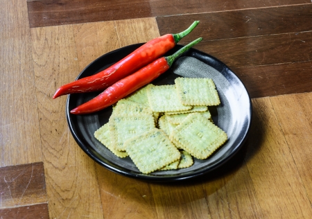 close up biscuits desert  and pepper on single black dish at brown wood paquet floor groundの写真素材