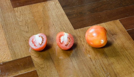 many tomato cut and single tomato at brown wood paquet floor groundの写真素材