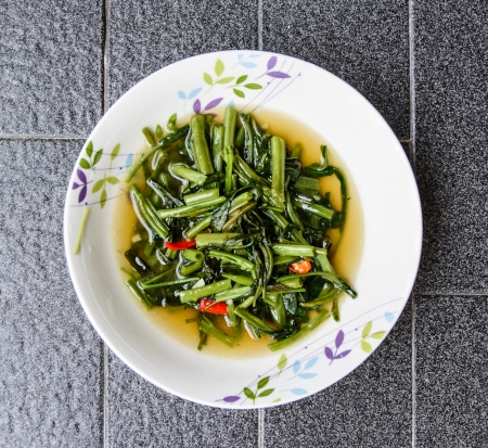 top view green morning glory fried oil food with pepper on grey tile backgroundの写真素材
