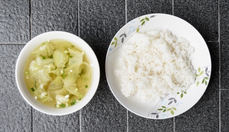 top view green lettuce and meat soup thailand style food in bowl with rice on grey tile backgroundの写真素材
