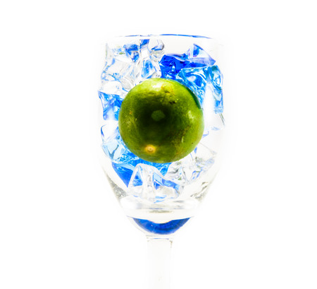 close up small green lemon and ice cube in small wine glass isolated on white backgroundの写真素材