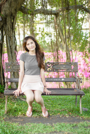 portrait asia young woman sitting and smile on outdoor sunrise at natural gardenの写真素材