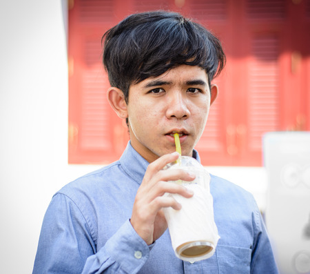 asia young Man drinking ice coffee water from plastic cup  at outdoor sunriseの写真素材