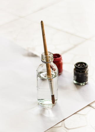 Old paintbrushes paints and color bottle with paper backgroundの写真素材