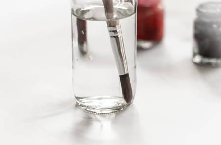 Old paintbrushes paints and color bottle with paper backgroundの写真素材