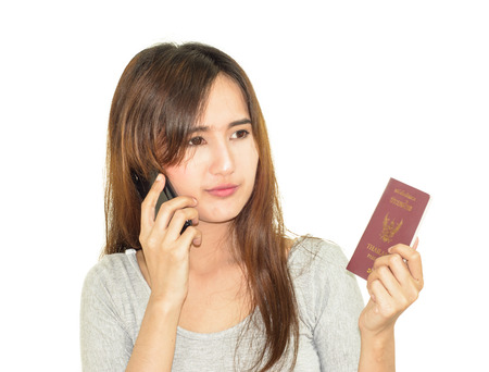 asia young woman use mobile phone and holding thailand passport isolated on whiteの写真素材