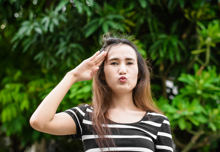 young cute asia woman saluting sign in a natural at outdoor sunriseの写真素材