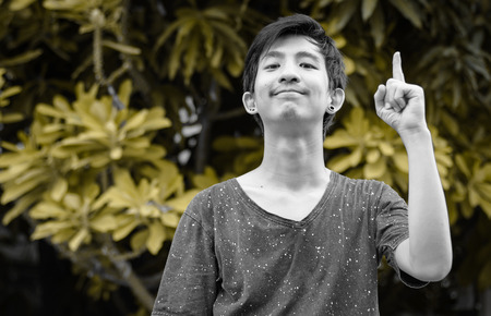 Young asian man pointing by him finger with retro filter at outdoor naturalの写真素材