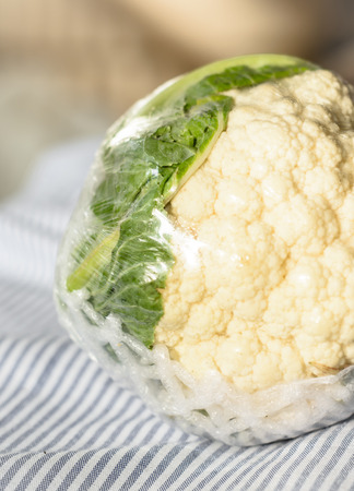 vegetable fresh cauliflower in plastic package on fabric pattern at outdoor sunriseの写真素材