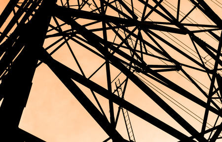 silhouette construction of high voltage tower on bright orange background