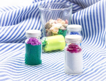 lovely decoration sand in bottle and small shell on fabric pattern background