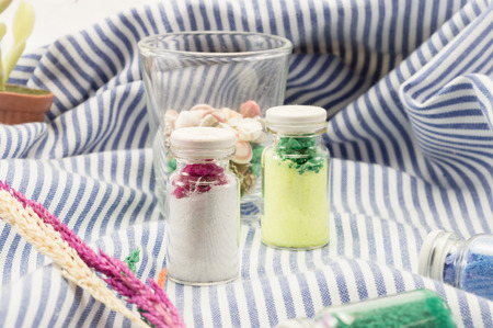 lovely decoration sand in bottle and small shell on fabric pattern backgroundの写真素材