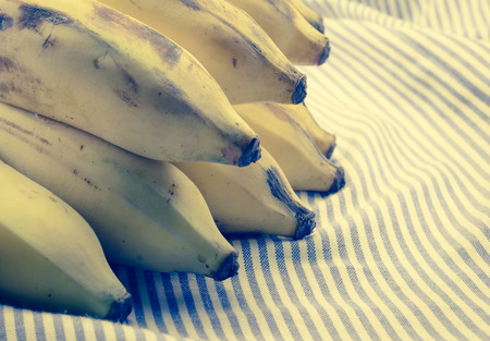 fruit yellow Bunch of ripe bananas with retro filter on fabric textile backgroundの写真素材