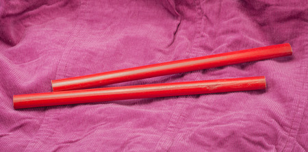 two red pencil on old fabric cotton backgroundの写真素材