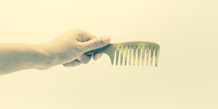 girl hand holding small plastic comb with retro filter on white backgroundの写真素材