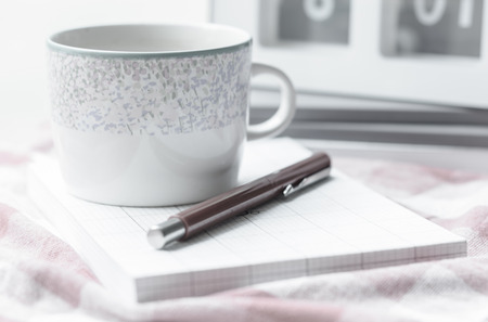 notebook and pen with coffee cup on fabric background at oudoor sunrise with retro filterの写真素材