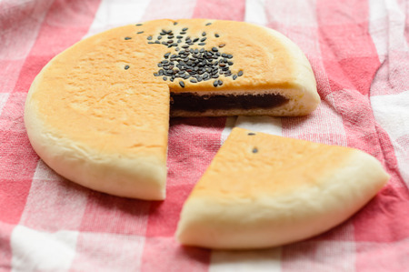 Red bean and black sesame filled bread on fabric background at outdoor tableの写真素材