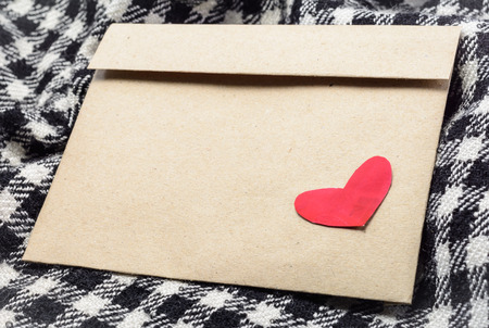 close up letter brown paper envelope with red heart at plaid fabric backgroundの写真素材