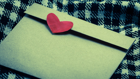 letter brown paper envelope with red heart at plaid fabric background with retro filterの写真素材