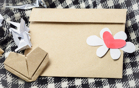 letter brown paper envelope with red heart and paper bird at plaid fabric background