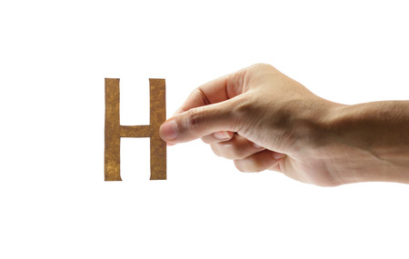 woman hand holding the brown letter h, isolated on white backgroundの写真素材