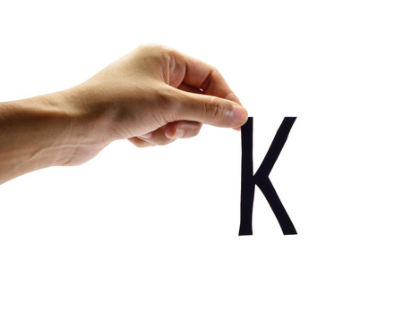 woman hand holding the black letter k, isolated on white backgroundの写真素材