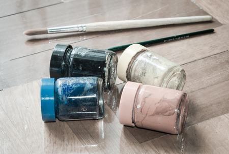 water color paint glass bottle and paintbrush on wood parquet background with retro filter