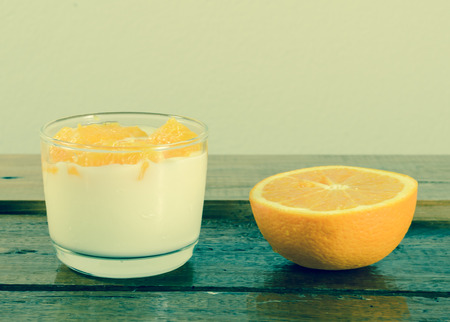 Healthy dessert Yogurt and fresh orange on wooden table with retro filterの写真素材