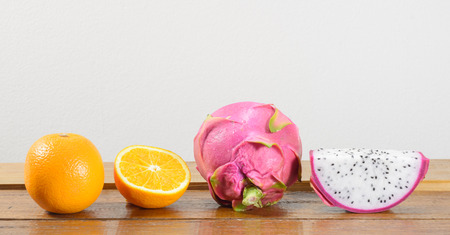ripe dragon fruit and orange fruit on wooden table on concrete backgroundの写真素材