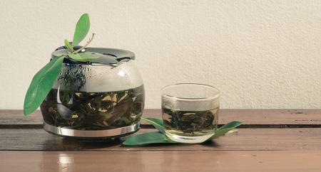 Teapot and glass cups with tea on wooden table with retro filterの写真素材