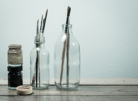old dirt Brush paints and water color bottle on wood table with retro filterの写真素材