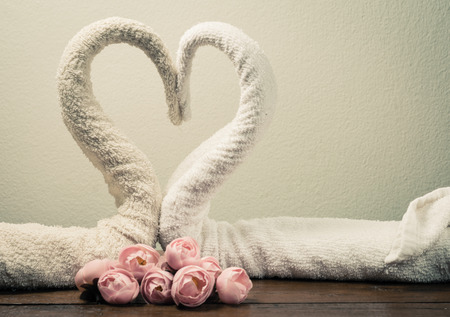 two white towels swans with heart sign on wood table with retro filterの写真素材