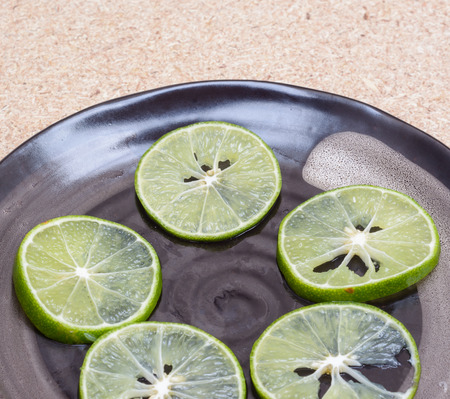 Fresh lemons slice on black dish at wood table backgroundの写真素材
