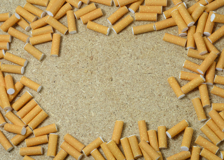 many cigarettes butts and copyspace at wooden table backgroundの写真素材
