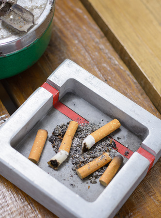 Cigarette butt and Metal ashtray on wooden table backgroundの写真素材