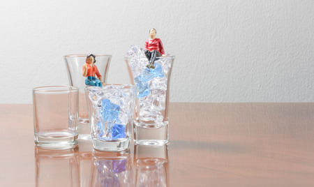 boy and girl figurine on ice cube and glass concept hot summer time dayの写真素材