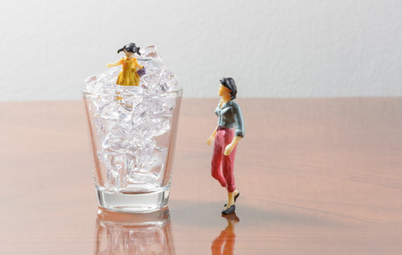 family figurine on ice cube and glass concept hot summer time dayの写真素材